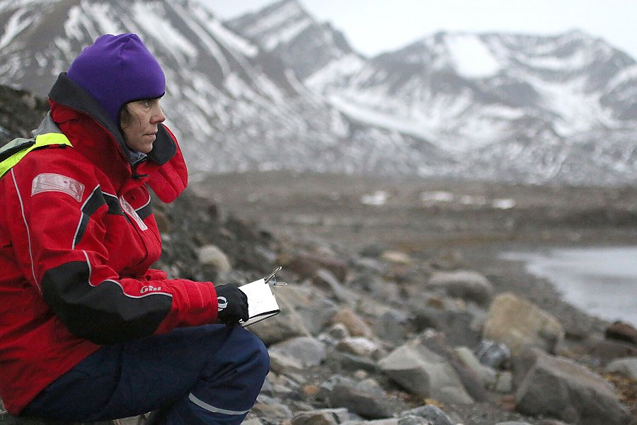 Woman wearing cold-weather clothes looks out on rocky shore