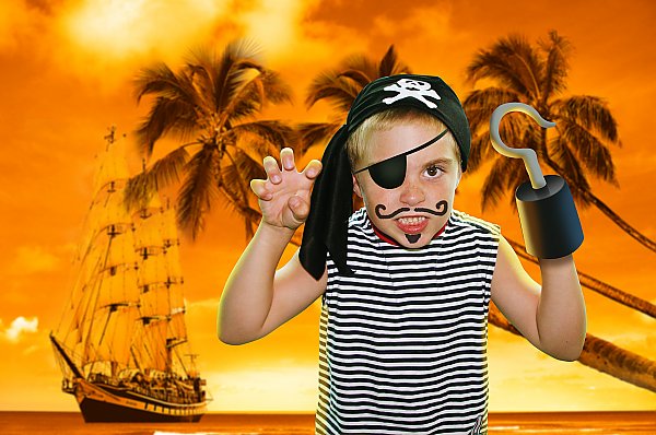 Boy dressed as a pirate for Halloween in front of tropical background