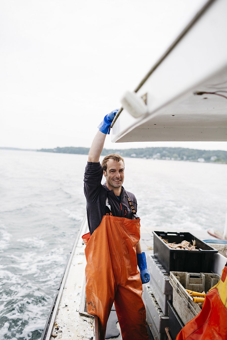 Chef Barton Seaver on a fishing boat with orange waders and blue gloves.