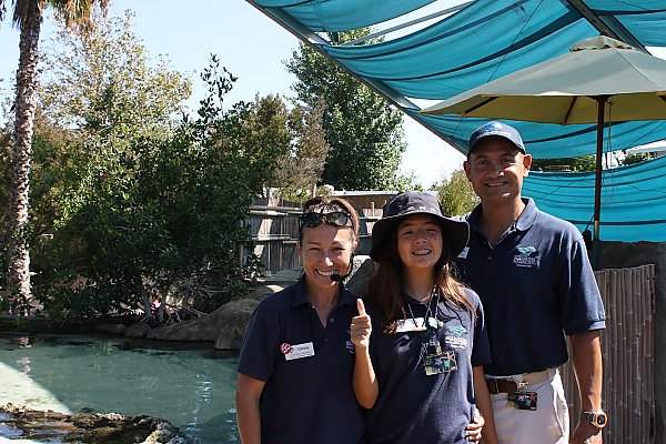 Teenager girl gives thumbs-up flanked by parents in Shark Lagoon.