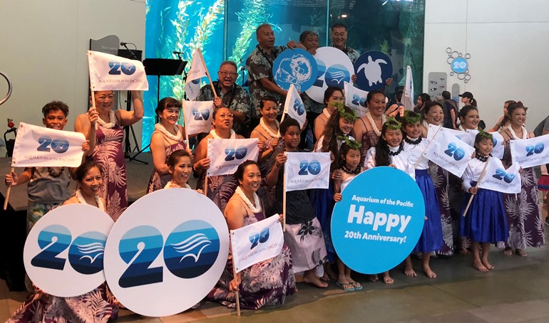 2018 Pacific Islander Festival participants with 20th Anniversary signs and flags