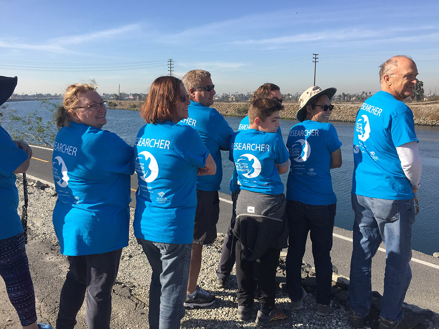 Several volunteers in blue shirts looking at the river