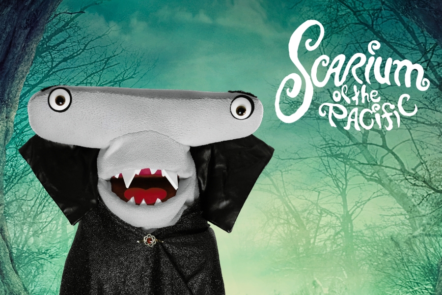 Seymour the hammerhead shark puppet wearing a vampire costume with the text/logo