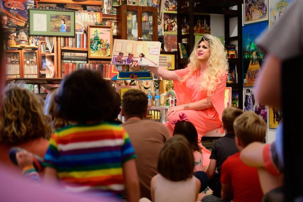 Drag queen holds book up to children during storytelling