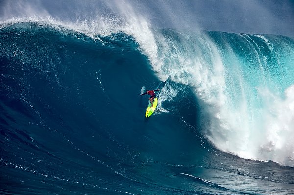 Big wave surfer Jamie Mitchell rides a surfboard down the face of a cresting wave