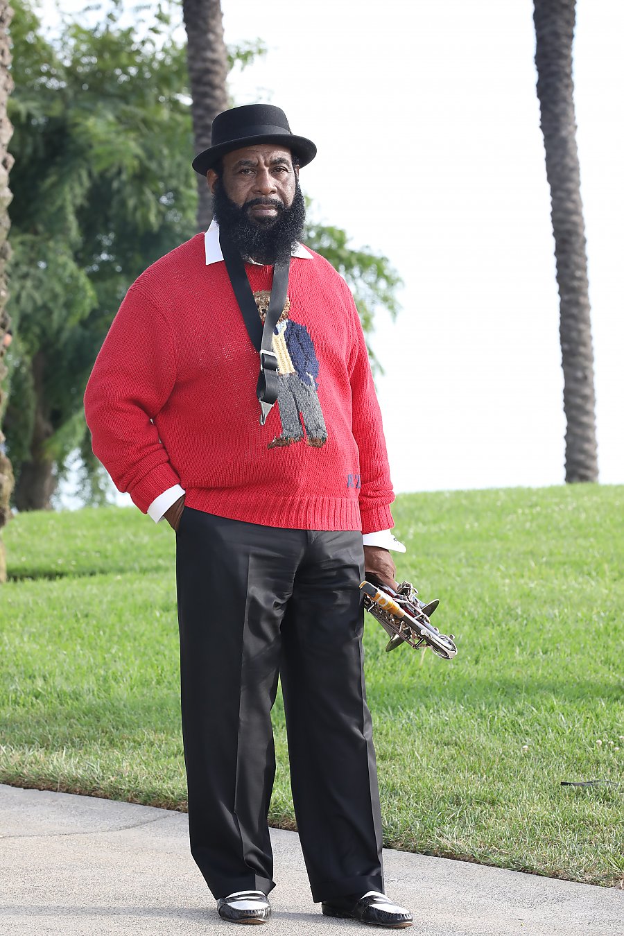 Man stands, holding a saxophone