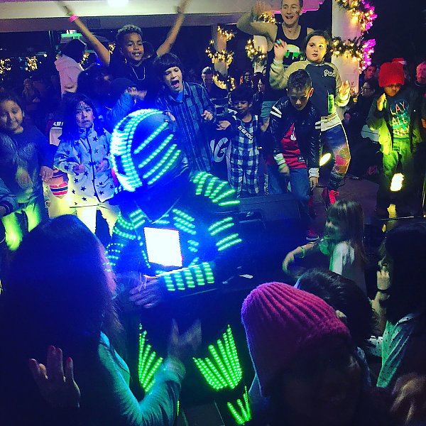 LED-lit Robot in a crowd of young dancers in a party