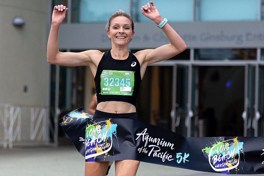 smiling woman crosses the finish line with arms raised