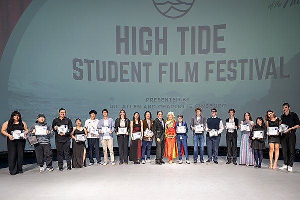 People holding certificates standing in front of a screen that says, "High Tide Student Film Festival"