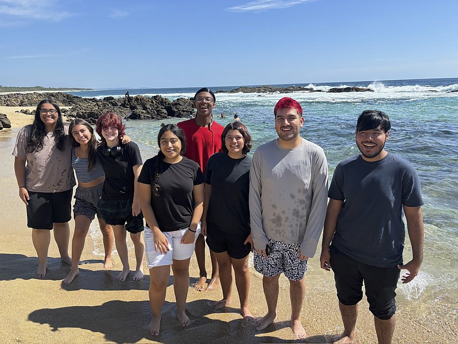 People standing on a sunny shoreline smiling