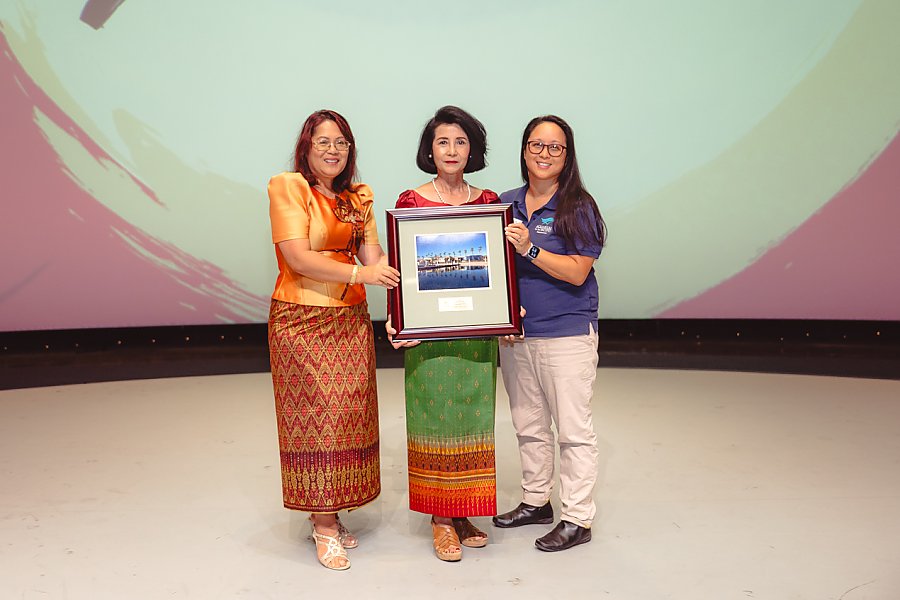 Three people holding a framed picture