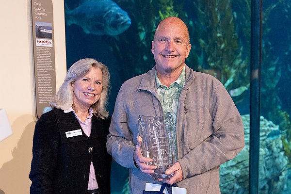 two people smiling; one person is holding a glass object
