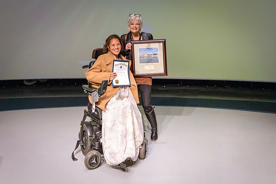 2 women smiling holding picture and certificate