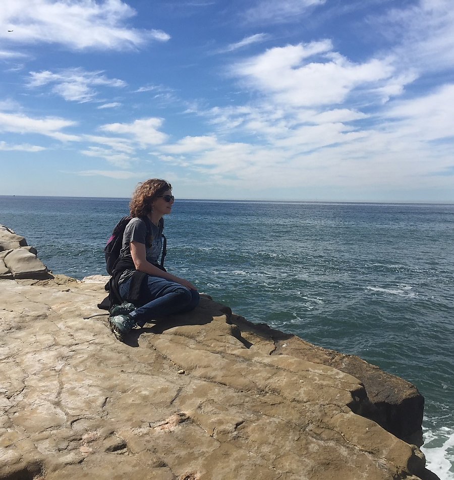 Sarah Newkirk from The Nature Conservancy sits on a rock and stares into the ocean blue.