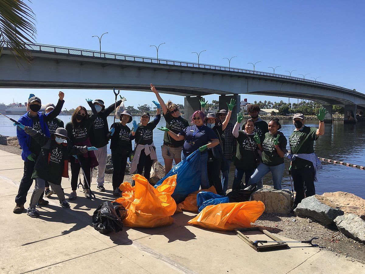 Group of people underneath bridge with beach cleanup bags