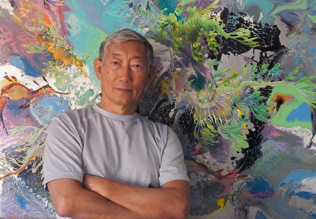 Photo of artist Truong Buu Giam standing with arms folded in front of one of his paintings