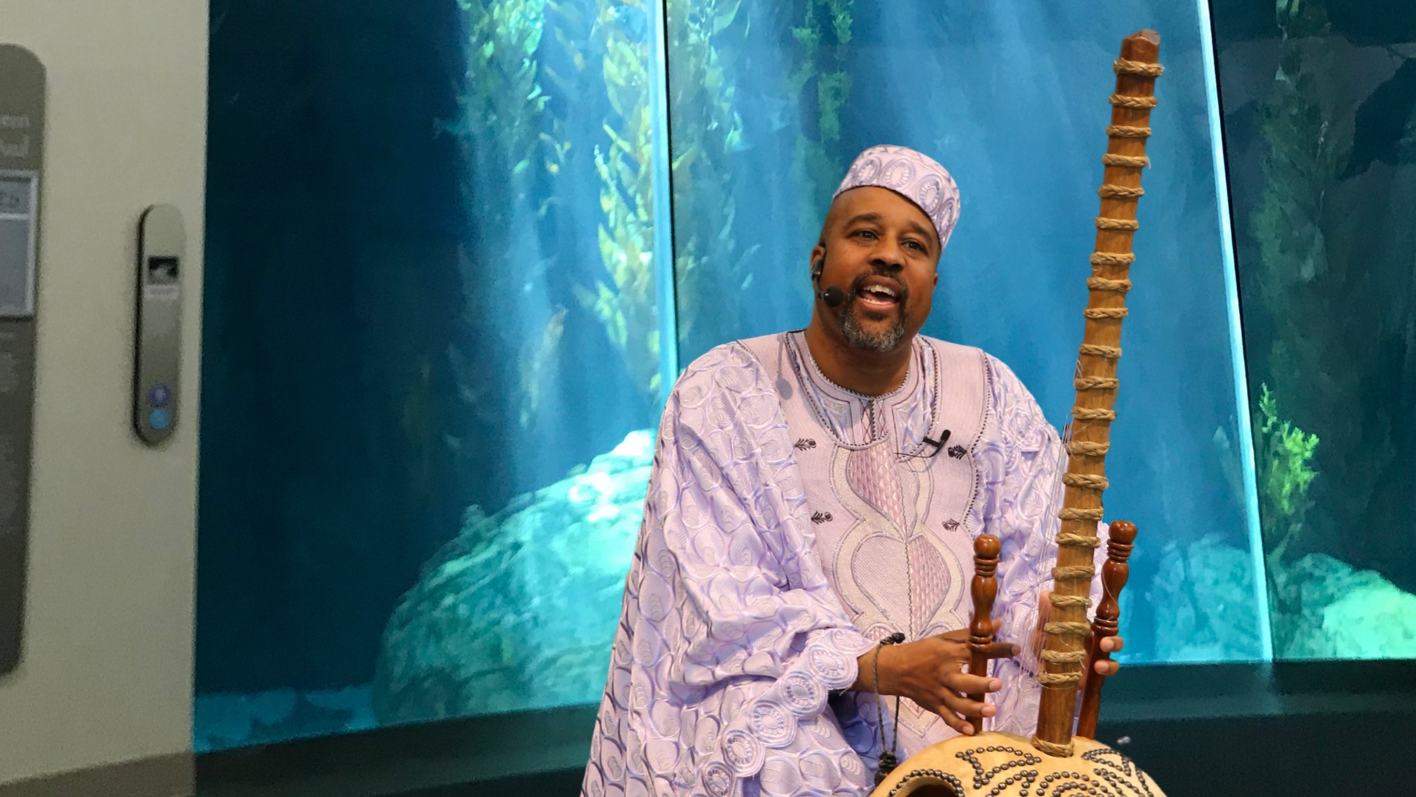 a man in front of an Aquarium habitat playing a kora